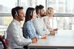 Side view happy multicultural call center operators sitting at desk. stock image Side view happy multicultural call center operators sitting at desk. stock image