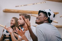 side view of multicultural group of male football fans gesturing by hands and watching soccer match royalty free stock image side view of multicultural group of male football fans gesturing by hands and watching soccer match royalty free stock image