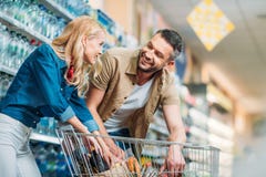 side view of smiling couple checking purchases in shopping cart stock photo side view of smiling couple checking purchases in shopping cart stock photo
