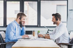 side view of smiling young call center operators in headsets using laptops stock image side view of smiling young call center operators in headsets using laptops stock image