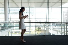 Side view of businesswoman using mobile phone in office and walking on a carpet walkway stock images Side view of businesswoman using mobile phone in office and walking on a carpet walkway stock images