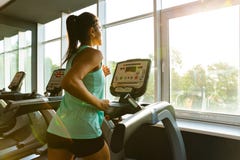 Side view of Young concentrated sports woman running on treadmill stock images Side view of Young concentrated sports woman running on treadmill stock images