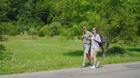 Sidosikt: ett ungt turist- par promenerar vägen till härliga berg som täckas med skogaktivlivsföringen stock video Sidosikt: ett ungt turist- par promenerar vägen till härliga berg som täckas med skogaktivlivsföringen stock video