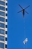 Commercial Helicopter carries a sign part to the top of a skyscraper