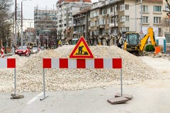 The sign of road works on red white barrier in front of a pile of gravel on a city street. Construction and repair of asphalt royalty free stock image The sign of road works on red white barrier in front of a pile of gravel on a city street. Construction and repair of asphalt royalty free stock image