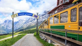 Sign of Starting point to begin walking trail with view of Swiss wengernalpbahn railways train departing Kleine Scheidegg station stock photography Sign of Starting point to begin walking trail with view of Swiss wengernalpbahn railways train departing Kleine Scheidegg station stock photography