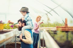 Signora bionda adorabile in cardigan rosa che pianta i fiori con poca vanga di giardinaggio Bambino barbuto della tenuta dell'uom immagini stock libere da diritti Signora bionda adorabile in cardigan rosa che pianta i fiori con poca vanga di giardinaggio Bambino barbuto della tenuta dell'uom immagini stock libere da diritti