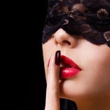 Silence. Femme sexy avec le doigt sur ses lèvres rouges montrant chut. Fille érotique avec le masque de dentelle au-dessus du noir images stock Silence. Femme sexy avec le doigt sur ses lèvres rouges montrant chut. Fille érotique avec le masque de dentelle au-dessus du noir images stock