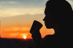 Silhouet van meisje met een kop van koffie bij zonsopgang stock fotografie Silhouet van meisje met een kop van koffie bij zonsopgang stock fotografie