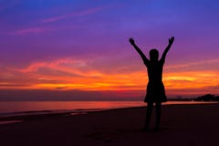 Silhouet van vrouw met handen omhoog terwijl status op overzees strand bij stock afbeelding Silhouet van vrouw met handen omhoog terwijl status op overzees strand bij stock afbeelding