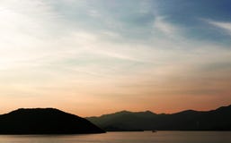 The silhouette of boat and mountain with gradient sunset. The silhouette of boat and mountain with the gradient sunset Stock Image The silhouette of boat and mountain with gradient sunset. The silhouette of boat and mountain with the gradient sunset Stock Image