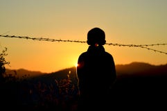 Silhouette of Boy Standing Near Barbed Wire Fence during Golden Hour Stock Images Silhouette of Boy Standing Near Barbed Wire Fence during Golden Hour Stock Images