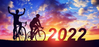 Silhouette of cyclists with bicycles at sunset. New Year 2022 concept.