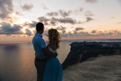 Silhouette d'un couple affectueux au coucher du soleil Homme embrassant avec une femme sur une haute montagne donnant sur la mer photographie stock libre de droits Silhouette d'un couple affectueux au coucher du soleil Homme embrassant avec une femme sur une haute montagne donnant sur la mer photographie stock libre de droits