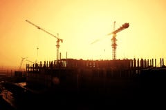 Silhouette d'une grue et d'un cadre d'un bâtiment en construction au fond de coucher du soleil photographie stock Silhouette d'une grue et d'un cadre d'un bâtiment en construction au fond de coucher du soleil photographie stock