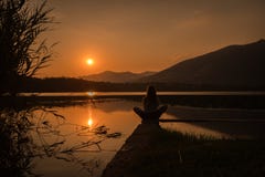 Silhouette de fille se tenant au-dessus de l'amountain de lac en position de yoga de loto image stock Silhouette de fille se tenant au-dessus de l'amountain de lac en position de yoga de loto image stock