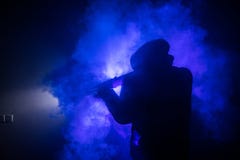 Silhouette de l'homme avec le fusil d'assaut prêt à attaquer sur le fond brumeux modifié la tonalité foncé ou le bandit dangereux photos stock Silhouette de l'homme avec le fusil d'assaut prêt à attaquer sur le fond brumeux modifié la tonalité foncé ou le bandit dangereux photos stock