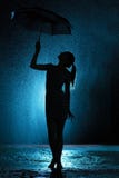 Silhouette du chiffre d'une jeune fille avec un parapluie sous la pluie, une jeune femme heureuse aux gouttes de l'eau photo libre de droits Silhouette du chiffre d'une jeune fille avec un parapluie sous la pluie, une jeune femme heureuse aux gouttes de l'eau photo libre de droits