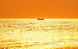 Silhouette of Fishermen on a fishing boat in the sea. And evening golden light. stock photo Silhouette of Fishermen on a fishing boat in the sea. And evening golden light. stock photo