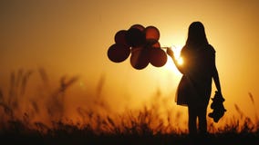 Silhouette of a girl with balloons and a teddy bear. It is worth the sunset. Farewell to childhood concept