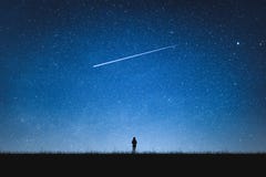 Silhouette of girl standing on mountain and night sky with shooting star. Alone concept