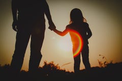 Silhouette of little girl holding parent hand at sunset royalty free stock photo Silhouette of little girl holding parent hand at sunset royalty free stock photo