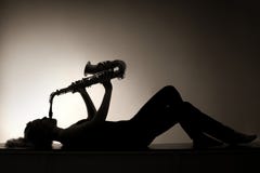 Silhouette of lying woman playing saxophone