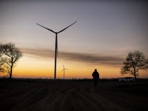 Silhouette of a man goes to sunset in the direction of wind turbines royalty free stock photos Silhouette of a man goes to sunset in the direction of wind turbines royalty free stock photos