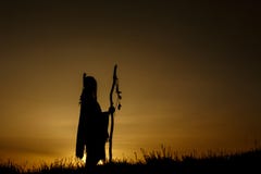 silhouette of native american shaman with pikestaff on background of sunset beutiful in mountains