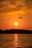 Silhouette of Passenger Airplane Landing at sunset. Above the sea Stock Image Silhouette of Passenger Airplane Landing at sunset. Above the sea Stock Image