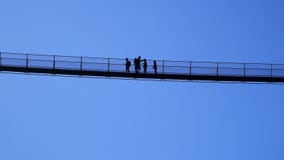 Silhouette of people walking on the highest tibetan bridge in Europe in the italian Alps.Ponte nel cielo.Valtellina