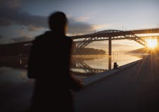 Silhouette of a person running at beautiful, early dawn under a bridge.