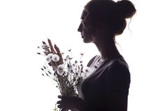 Silhouette portrait of a girl with a bouquet of dry flowers, face profile of a dreamy young woman on a white isolated background stock photography Silhouette portrait of a girl with a bouquet of dry flowers, face profile of a dreamy young woman on a white isolated background stock photography