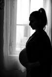 Silhouette of Pregnant Woman Standing next to the Window stock photography Silhouette of Pregnant Woman Standing next to the Window stock photography