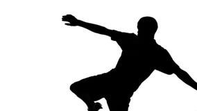 Silhouette of soccer player kicking ball