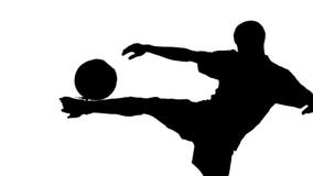 Silhouette of soccer player kicking ball