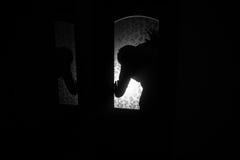 Silhouette of an unknown shadow figure on a door through a closed glass door. The silhouette of a human in front of a window at royalty free stock photography Silhouette of an unknown shadow figure on a door through a closed glass door. The silhouette of a human in front of a window at royalty free stock photography