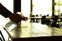 Silhouette waiter cleaning the table with disinfectant spray in a restaurant. royalty free stock photography Silhouette waiter cleaning the table with disinfectant spray in a restaurant. royalty free stock photography