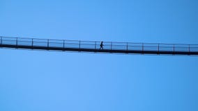 Silhouette of a woman walking on the highest Tibetan bridge in Europe in the italian Alps.Ponte nel cielo, sky bridge