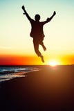 Silhouette young woman jumping with hands up on the beach at the Royalty Free Stock Photos Silhouette young woman jumping with hands up on the beach at the Royalty Free Stock Photos