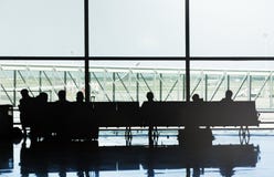 Silhouetten van mensen die op de stoelen van een luchthaven zitten die op hun vlucht wachten royalty-vrije stock fotografie Silhouetten van mensen die op de stoelen van een luchthaven zitten die op hun vlucht wachten royalty-vrije stock fotografie