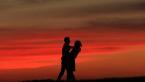 Silhouettes des beaux couples heureux embrassant doucement au-dessus du coucher du soleil rouge clips vidéos Silhouettes des beaux couples heureux embrassant doucement au-dessus du coucher du soleil rouge clips vidéos