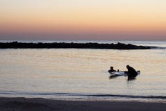 Silhouettes des personnes en mer dans le coucher du soleil photos stock Silhouettes des personnes en mer dans le coucher du soleil photos stock