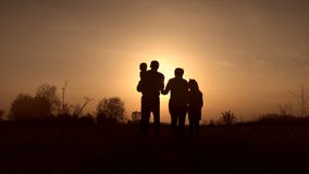 Silhouettes of grandparents with kids at sunset