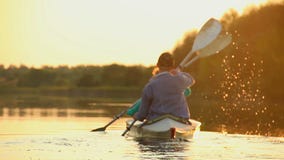 Silhouettes of tourists paddling kayak, teamwork, togetherness