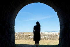 Silhueta da mulher em um túnel de pedra antigo foto de stock Silhueta da mulher em um túnel de pedra antigo foto de stock