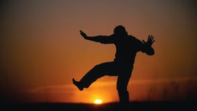 A silhueta do capoeira de execução da acrobata masculina engana no monte no por do sol filme A silhueta do capoeira de execução da acrobata masculina engana no monte no por do sol filme