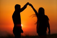 Silhuetas de um par loving no por do sol O conceito do amor e romance fotografia de stock Silhuetas de um par loving no por do sol O conceito do amor e romance fotografia de stock