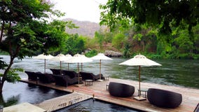 Silla de cubierta o daybeds y paraguas en balsa de la costa en centro turístico cerca del río Kwai Kanchanaburi, Tailandia Silla de cubierta o daybeds y paraguas en balsa de la costa en centro turístico cerca del río Kwai Kanchanaburi, Tailandia