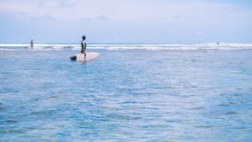 Silueta de la mujer del ajuste que va a practicar surf en el mar y que mira para agitar el borde en horizonte en la isla de Bali, imagenes de archivo Silueta de la mujer del ajuste que va a practicar surf en el mar y que mira para agitar el borde en horizonte en la isla de Bali, imagenes de archivo